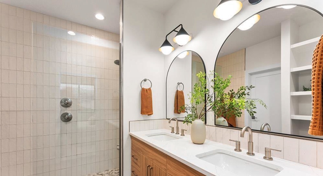 Bathroom with tiled shower, backsplash, and double vanity