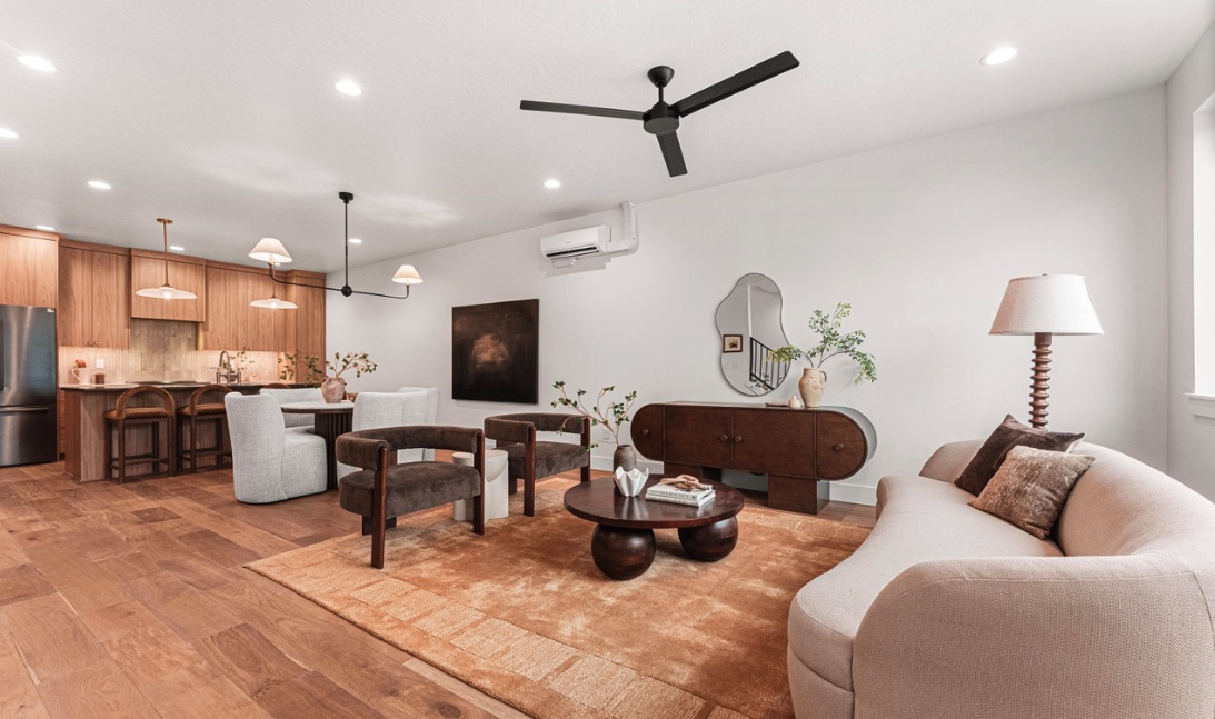 Open living room with warm wood flooring extending into the kitchen