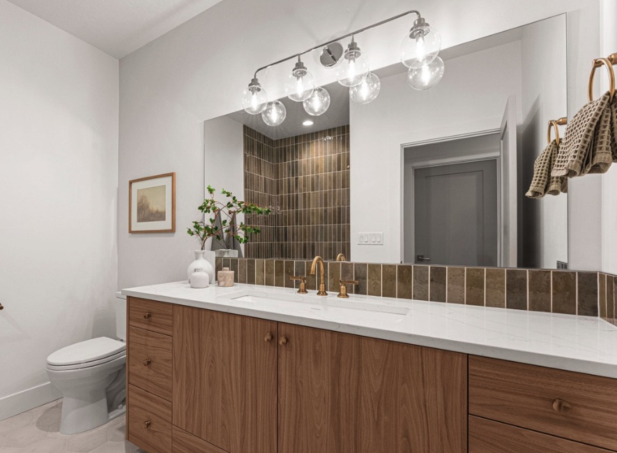 Bathroom vanity with a tiled backsplash and tiled shower reflection